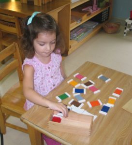 A little girl is playing with blocks on the table.