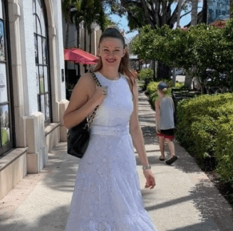 A woman in white dress walking down the street.