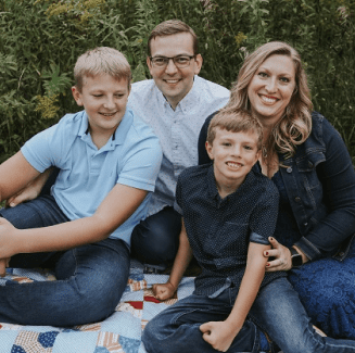 A family sitting on the ground with trees in the background