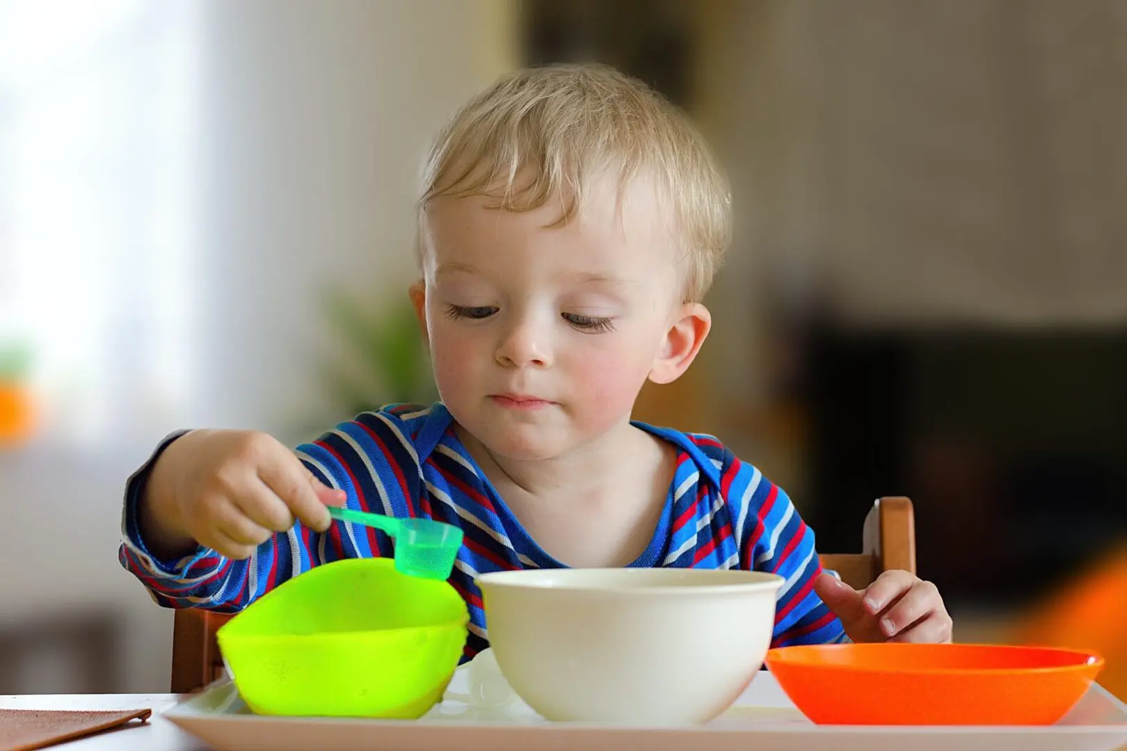 A young boy is eating from two bowls.