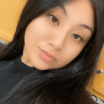 A young woman with long dark hair wearing a black top.